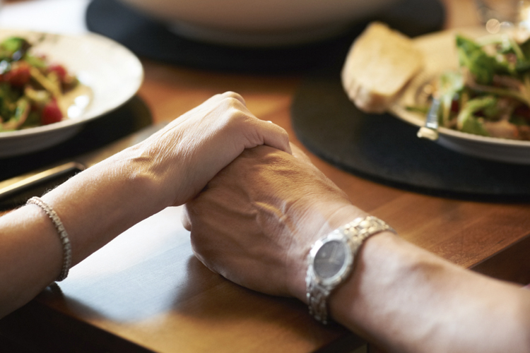 Elderly Couple Holding Hands at Dinner