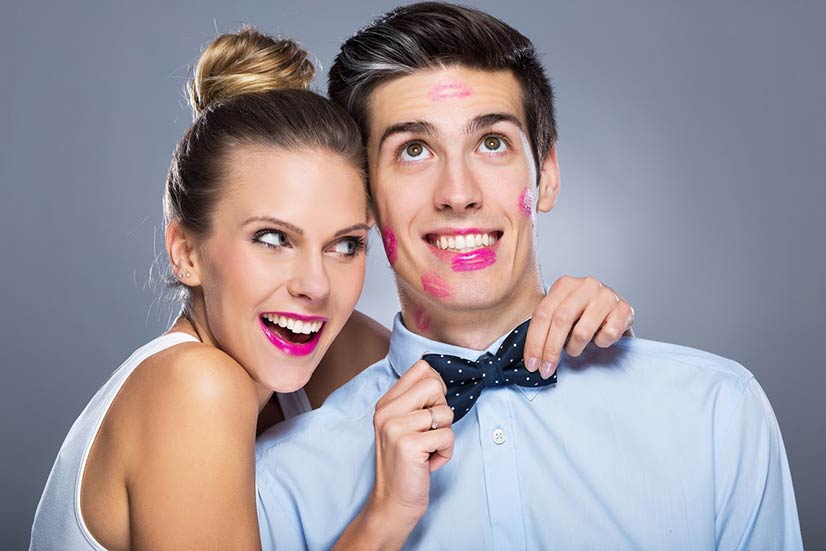 girl adjusting a boy's bowtie who has lipstick on his face